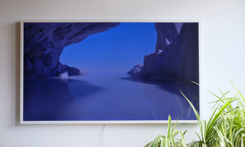 Photograph of Samsung The Frame TV mounted to wall with some spider plants in bottom right corner